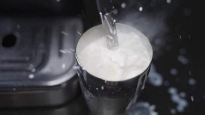 咖啡师慢动作在起泡的水罐中蒸牛奶。蒸汽棒加热牛奶。由于错误而溅起的牛奶。溢出牛奶失败。
