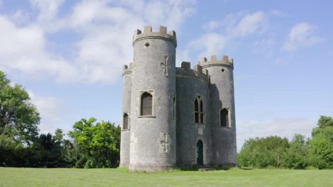 在阳光明媚的日子里，空中移动超过18世纪的哥特式英国愚蠢城堡，有三座炮塔，在阳光明媚的日子里，远处可