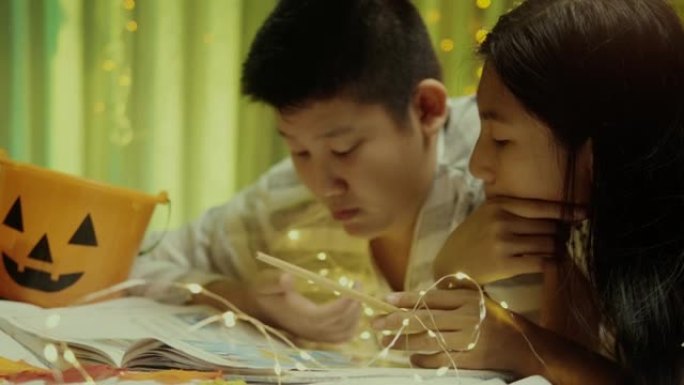 快乐的亚洲男孩和他的妹妹在晚上一起在床上看书。生活方式概念。