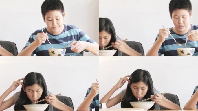 快乐的亚洲儿童在家一起在餐桌上吃方便面汤，生活方式理念。