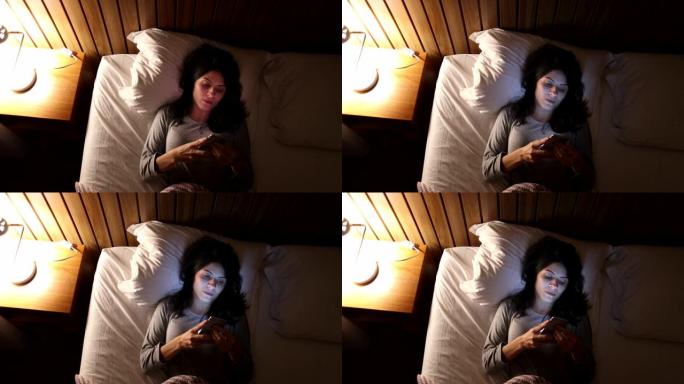 躺在床上的女人拿起手机并在睡觉前打开屏幕