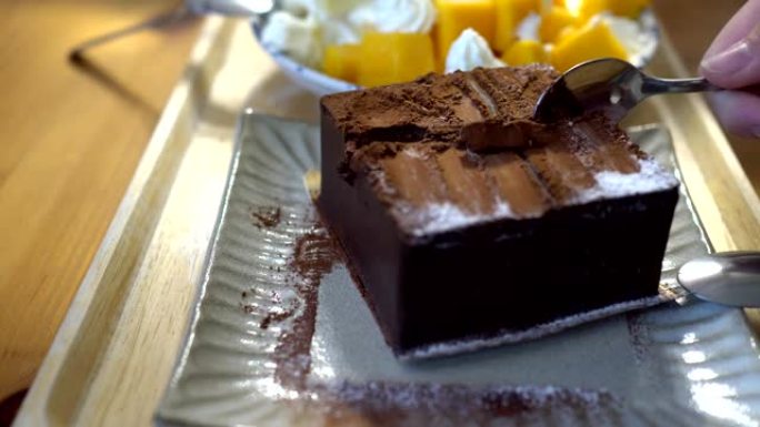 小女孩在餐馆吃甜点。盘子上的巧克力蛋糕和芒果蛋糕的特写。