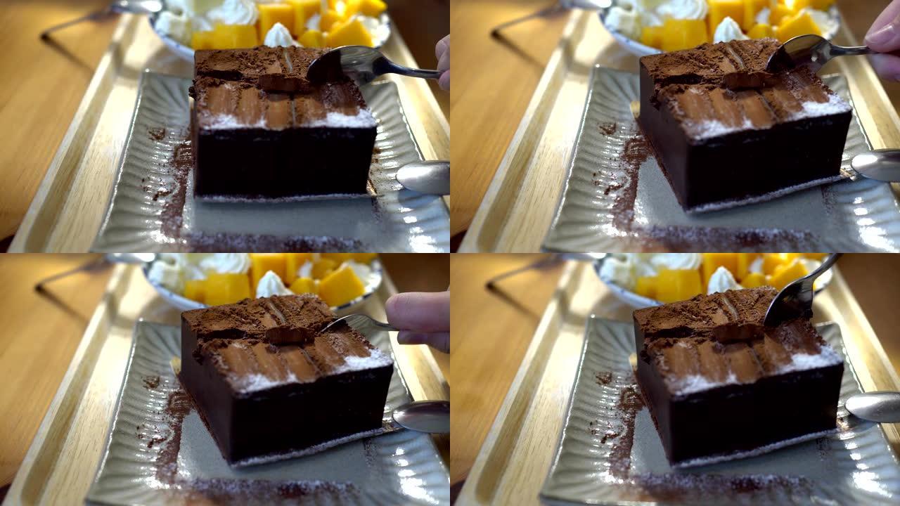 小女孩在餐馆吃甜点。盘子上的巧克力蛋糕和芒果蛋糕的特写。