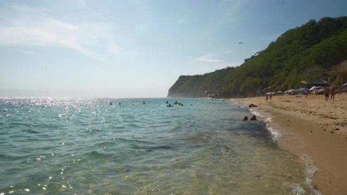 阳光灿烂的巴厘岛著名的melasti海滩拥挤的海岸线慢动作全景4k印度尼西亚