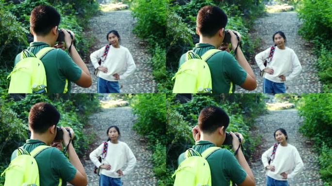 亚洲背包客男孩在度假旅行中为他的妹妹在森林里拍照。