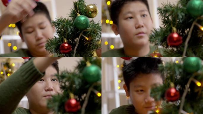快乐的亚洲男孩穿着绿色毛衣和红色发带装饰圣诞树，晚上在家，假期概念。