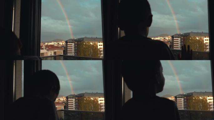 可爱的小男孩正从窗户看彩虹