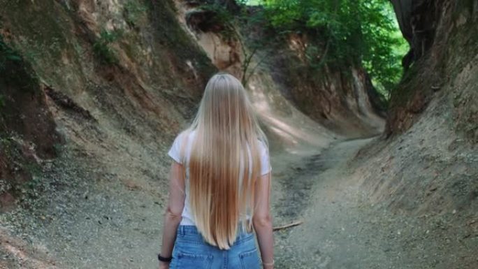 美丽的金发女人走在自然黄土峡谷中的背景图