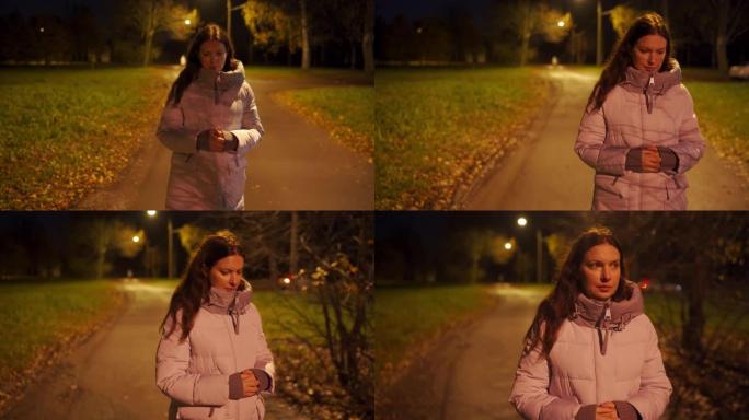 穿着温暖外套的孤独女人走在晚上被灯笼照亮的空人行道上