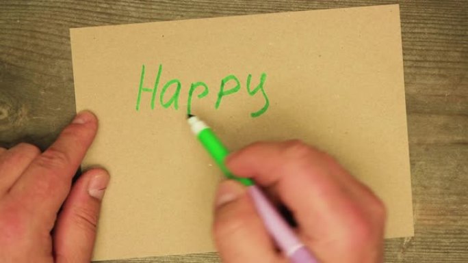 一只男性用绿色毡尖笔在纸板上写下新年快乐