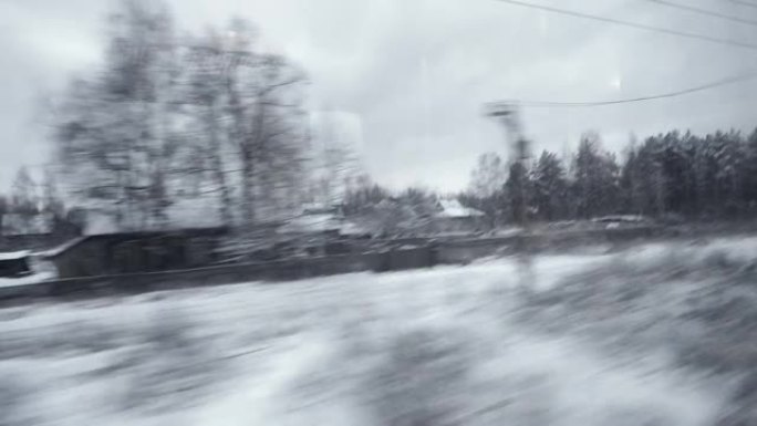 冬季森林和村庄穿过火车的窗户。
