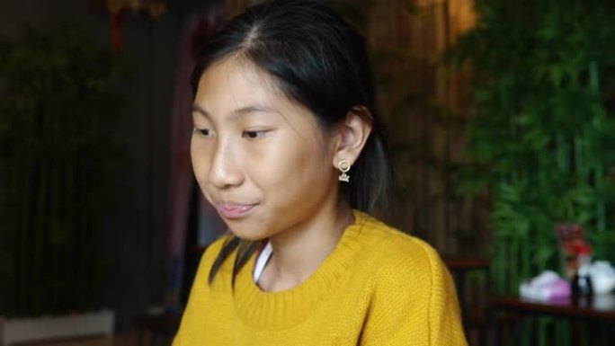 快乐的亚洲女孩穿着黄色毛衣测试芥末，一边等待她与家人、生活方式概念一起订购的食物。