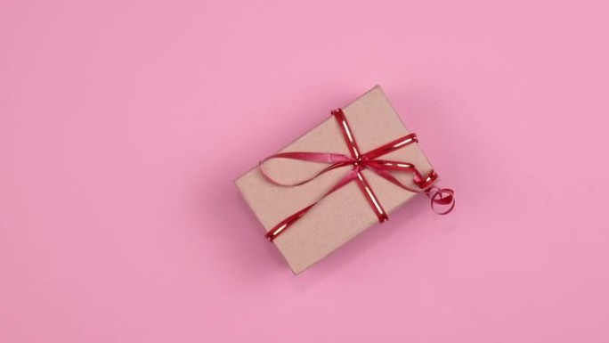 长方形工艺纸礼品盒，带丝带和蝴蝶结旋转特写，粉色背景，无缝循环运动