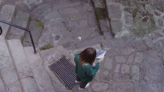 年轻的旅游妇女正在旧城区行走，使用纸质地图导航