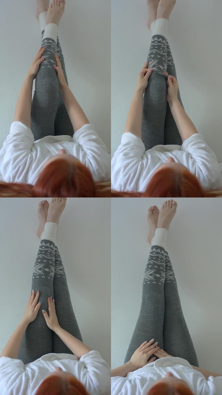 女人穿上温暖的灰色羊毛打底裤，冬天的女人的腿打底裤，垂直视频