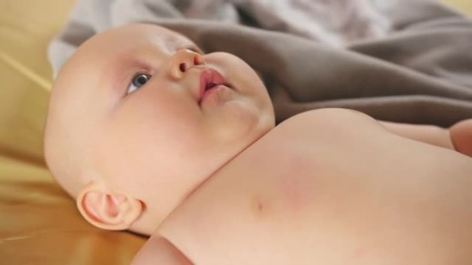 一个胖乎乎的四个月微笑的婴儿躺在床上。特写镜头。