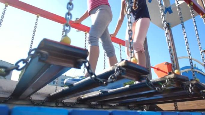 两个小姐妹的低角度镜头在海洋主题的操场上玩得开心。在阳光明媚的夏日通过障碍赛景点的女孩。50 fps
