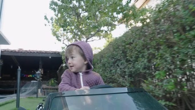 在新型冠状病毒肺炎大流行期间，男婴在家后院开车玩游戏。