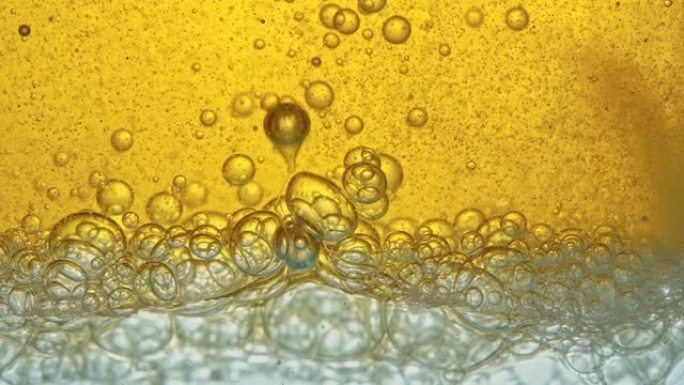 燃料，黄色，金色的油，倒入实验室的玻璃容器中，释放出类似于泡沫的气泡。