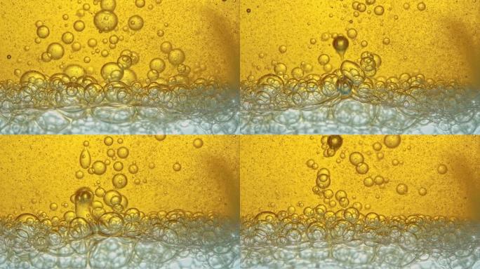 燃料，黄色，金色的油，倒入实验室的玻璃容器中，释放出类似于泡沫的气泡。