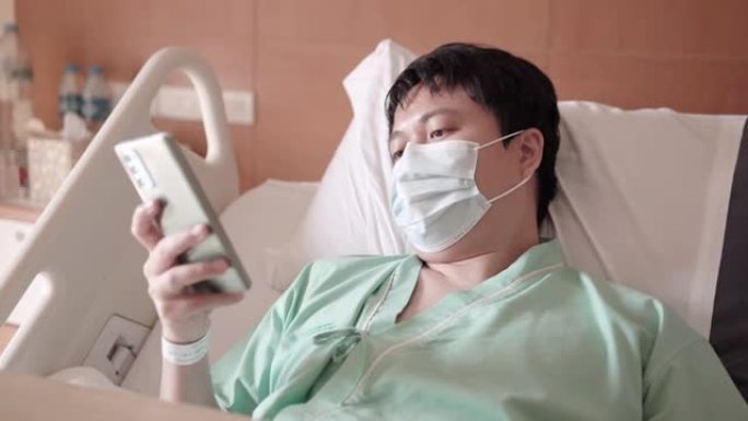 男性亚裔患者在医院病房使用电话。