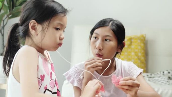快乐的亚洲儿童在家一起制作ASMR零食咬音的YouTube内容，周末活动概念。