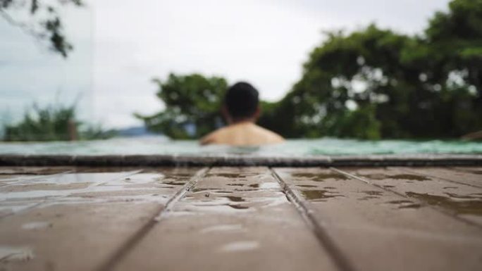 亚洲青年男子在游泳池放松一天假期