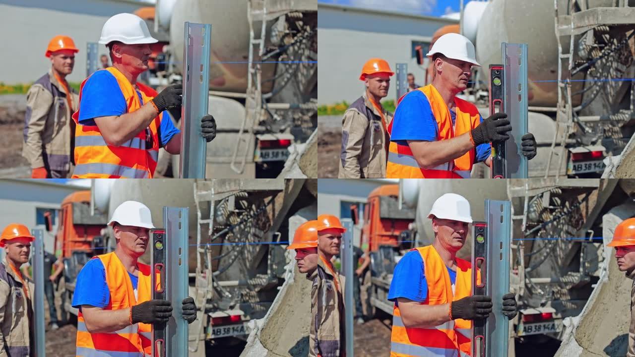 建筑工地。工人戴着安全安全帽在户外测量金属底座。建筑商准备在地面上安装太阳能电池板的基础。