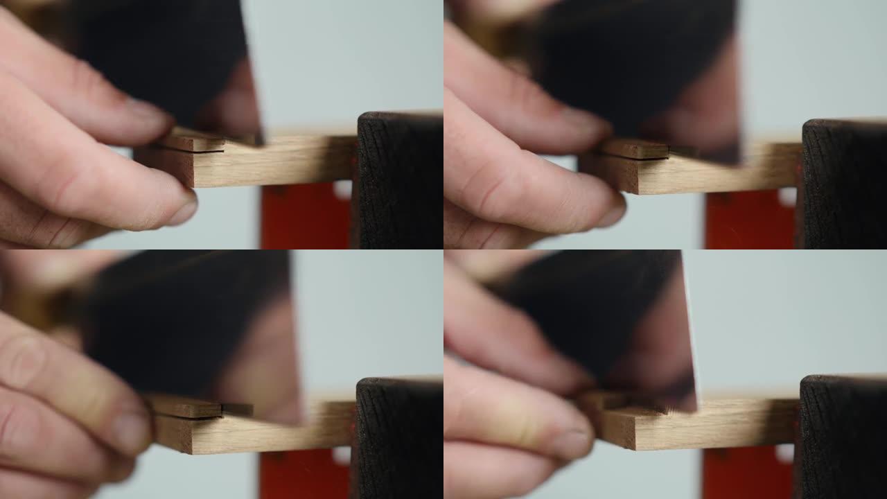 细木工用日本手锯在木制橡木坯料上锯出凹槽。手工木工。木工工具的声音