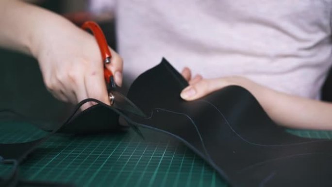 熟练的设计师切割黑色皮革制作面膜