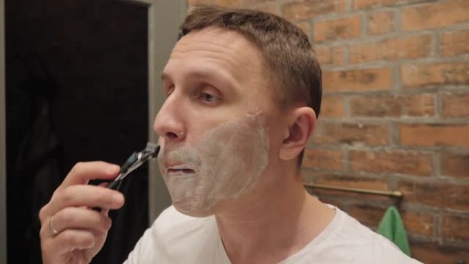 一个男人在刮胡子时鼓起脸颊。