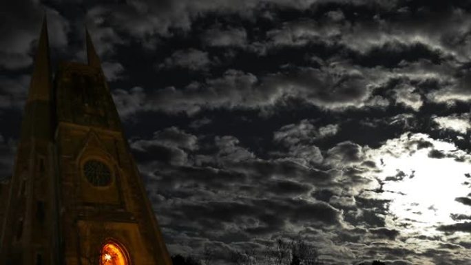 在月亮的照耀下，一字排开的云在黑暗的塔尖上飘荡