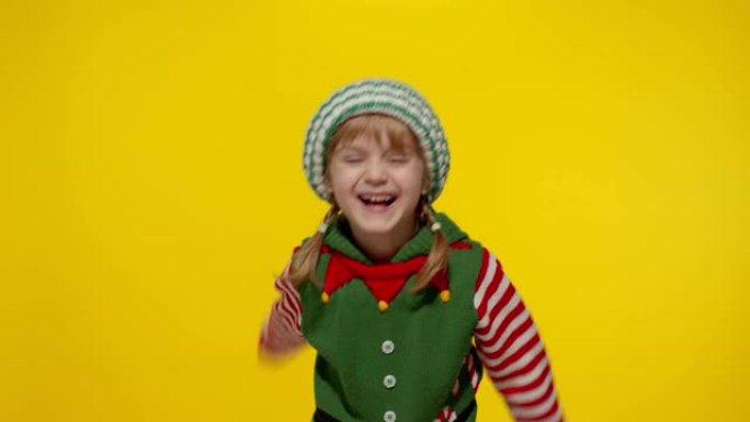 穿着圣诞精灵圣诞老人帮手服装的小女孩孩子表现出竖起大拇指的姿态。新年假期