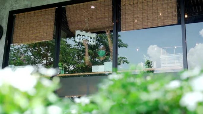 企业主亚洲男子戴着防护口罩在她的餐厅悬挂开放标志