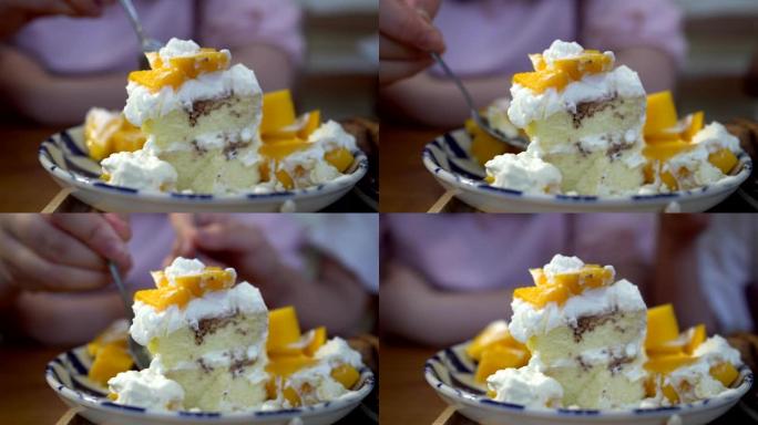 小女孩在餐馆吃甜点。盘子里芒果蛋糕的特写。芒果蛋糕快完成了。