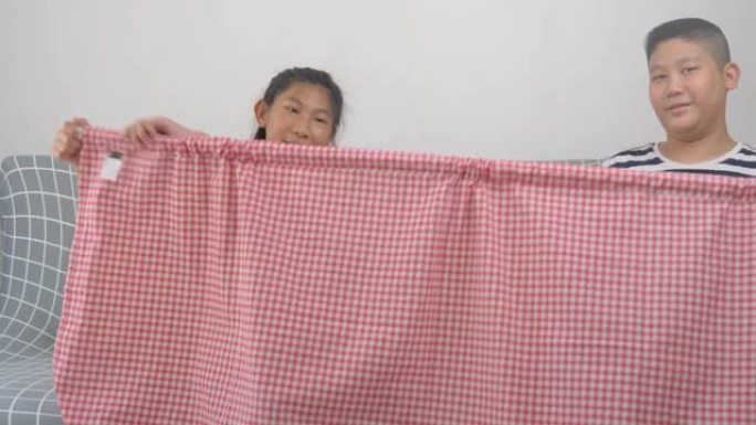 亚洲儿童在家一起安装带导轨的织物窗帘，自制概念。