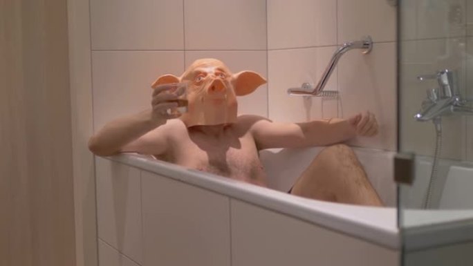 穿着猪面具的男人在4k慢动作60fps下班后在浴缸里放松，喝鸡尾酒