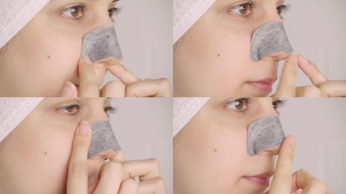一个女人在鼻子上贴了一条清洁条。鼻子上的黑点。浴室里没有化妆的女孩。皮肤护理，问题皮肤，清洁。自然美