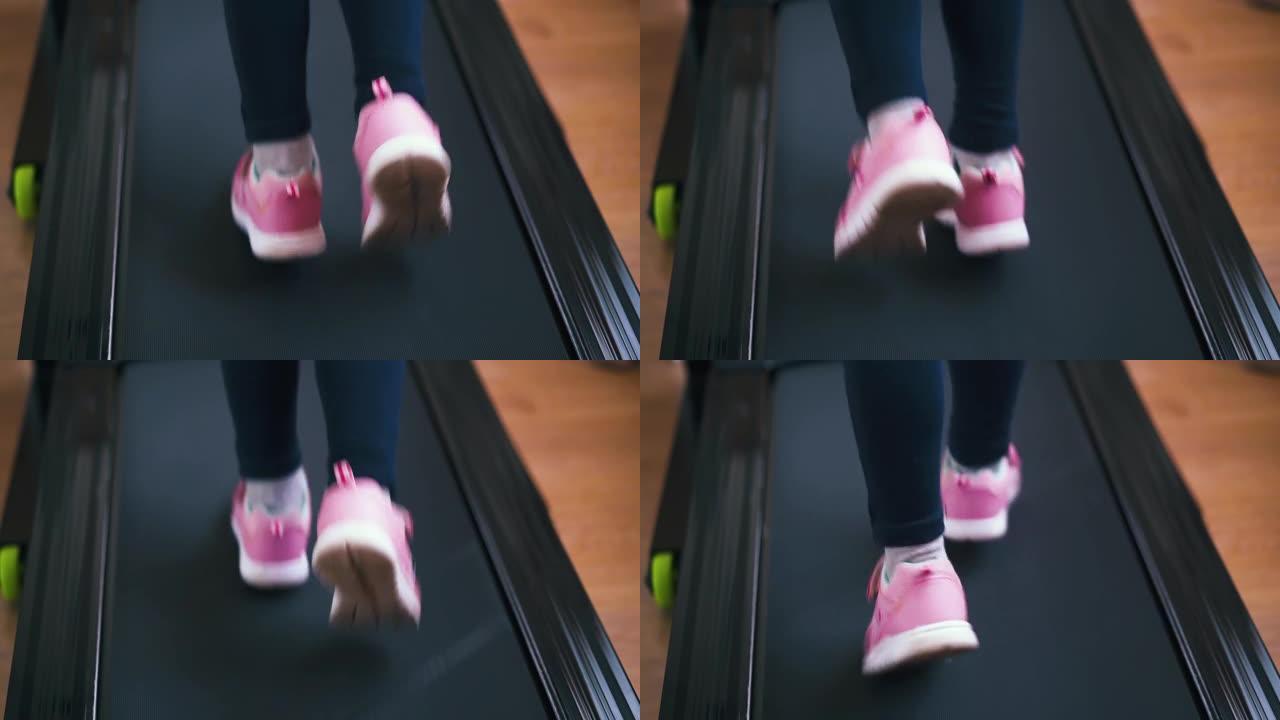穿着粉红色运动鞋的活跃女孩在家里的运动员跑道上奔跑