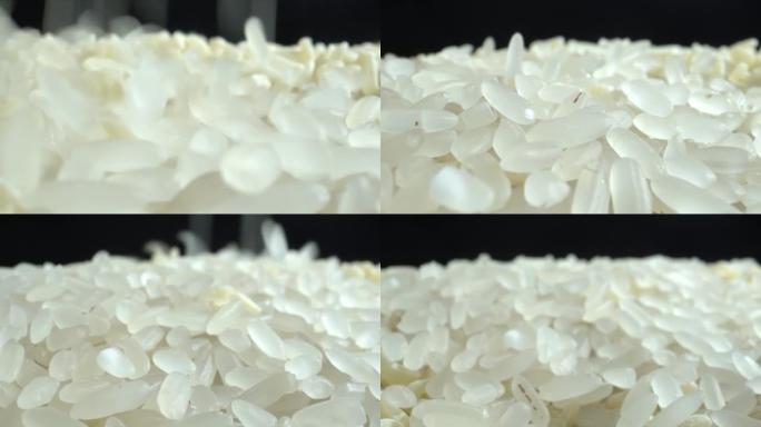 白米粒正落在黑桌上特写。把米饭扔在一堆米饭上。食物背景。滴米粒。