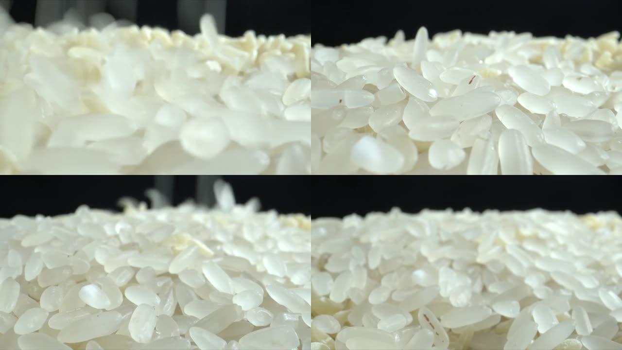 白米粒正落在黑桌上特写。把米饭扔在一堆米饭上。食物背景。滴米粒。