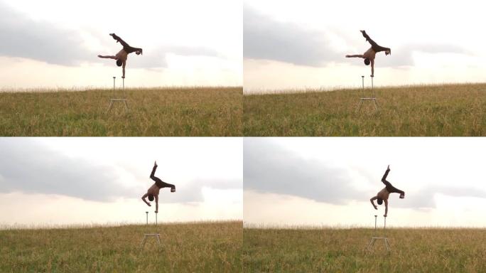 一个有运动能力的人在sunsetA的田野里进行复杂的体操运动，一个有运动能力的人在日落时在田野里进行