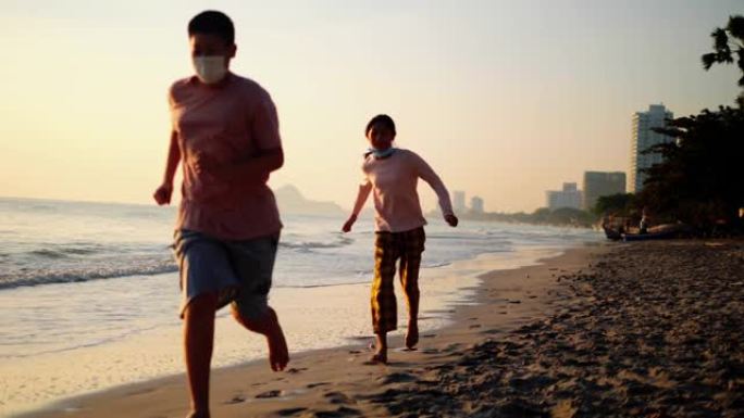 快乐的亚洲孩子早上一起在沙滩上奔跑，带着阳光，度假概念。