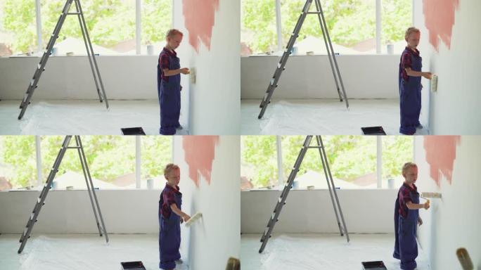 欧洲样貌的男孩用滚筒粉刷房子的墙壁。父母帮助概念