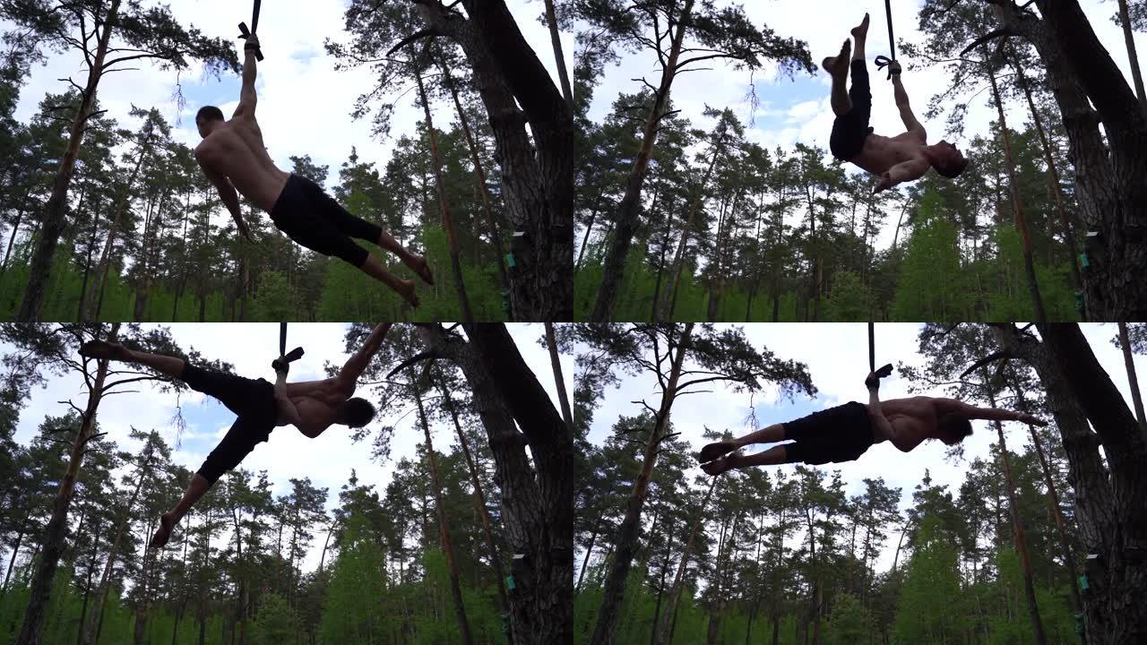 马戏团艺术家在绿色公园用空中绑带慢动作制作健美操