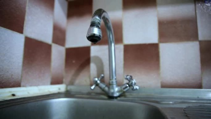 软焦点视频。厨房里的旧水龙头坏了。滴水。修理泄漏的水龙头。特写视图。
