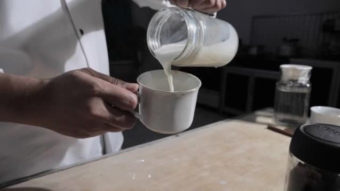 制作热奶油咖啡，咖啡师酒吧管理员将鲜奶油倒入咖啡杯中