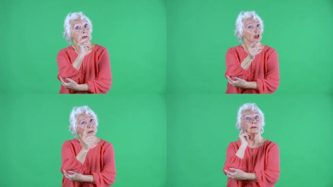 肖像老年妇女看着镜头责骂某人，并威胁摇晃食指。不要做那个手势。工作室绿色屏幕上穿着红色上衣的白发祖母