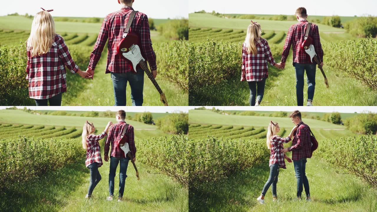 春日在田野里的男人和女人。恋爱中的情侣在春天的田野里度过时光。背景上的草。有电吉他的人。