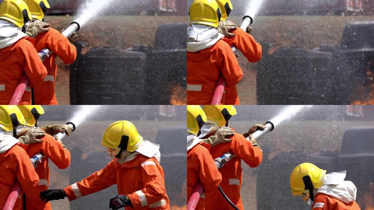消防队员团队灭火救援职责。三名身穿防火服的消防员从消防水带中喷水，扑灭训练区燃烧场所的crack啪作